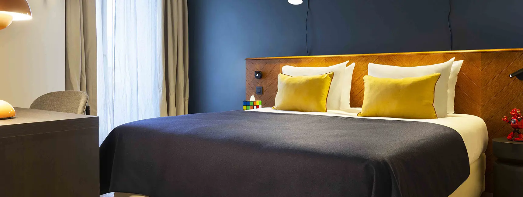 Vue inversée du lit double avec grande fenêtre et robot rouge – penthouse RockyPop Grenoble