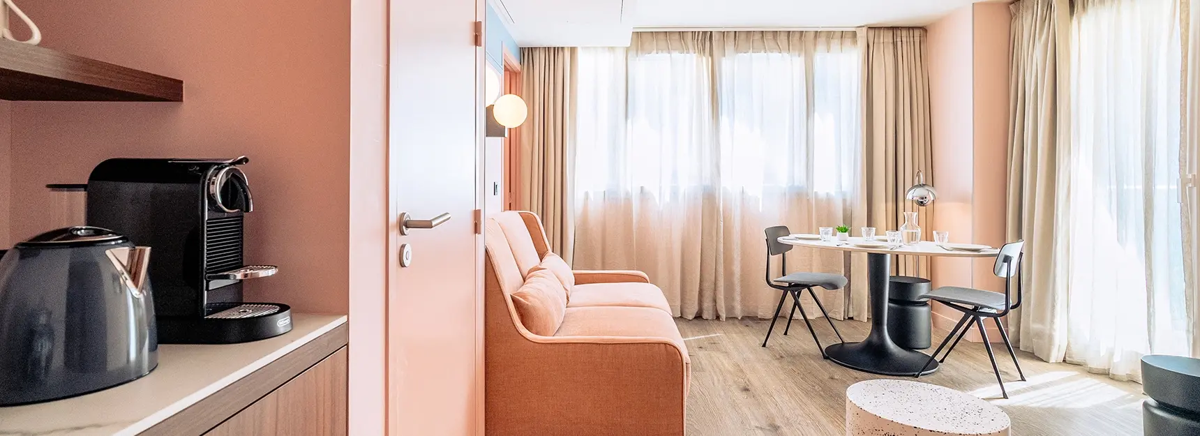 Coin salon avec canapé à gauche, une table dressée au fond et deux grande fenêtre dont un balcon - rockypop marseille