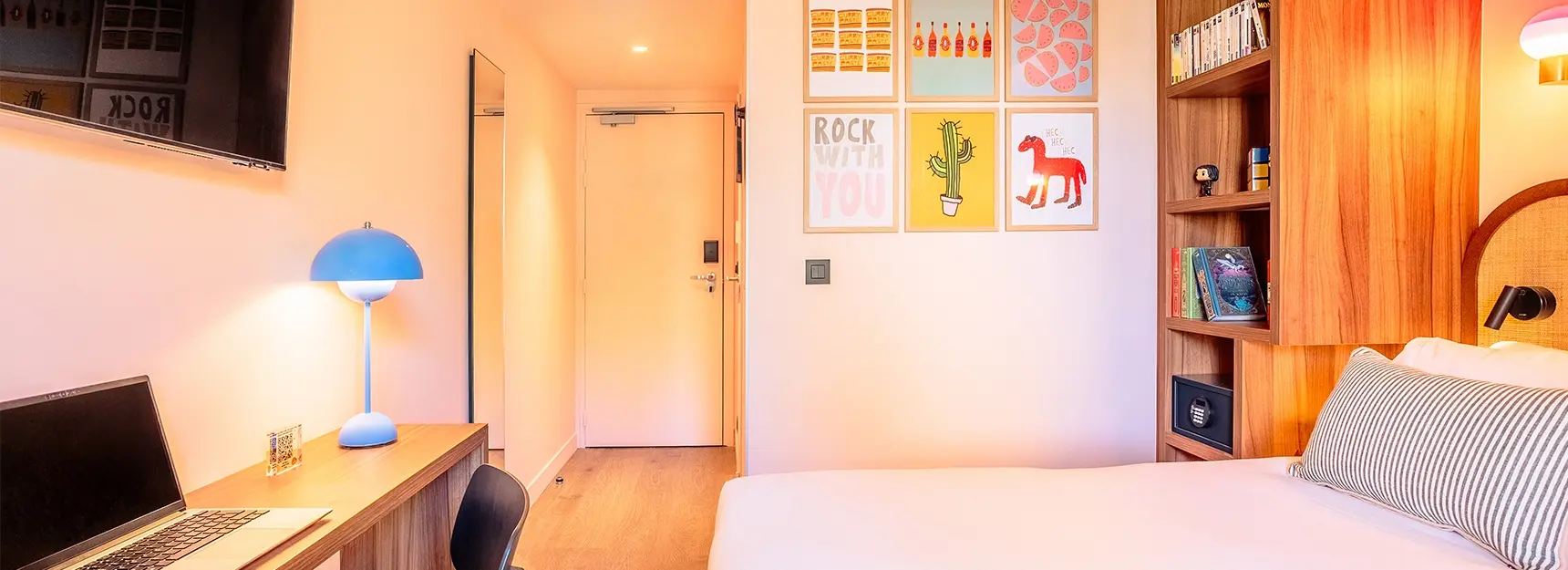 Vue sur lit double à droite, bureau avec chaise à gauche, porte au fond – chambre RockyPop Marseille