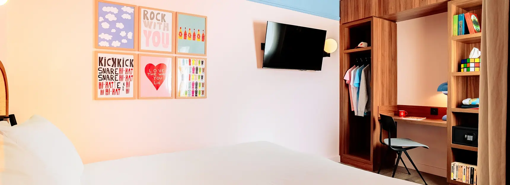 Chambre avec lit à gauche, cadres colorés au centre, TV et coin bureau avec rangements à droite - rockypop marseille
