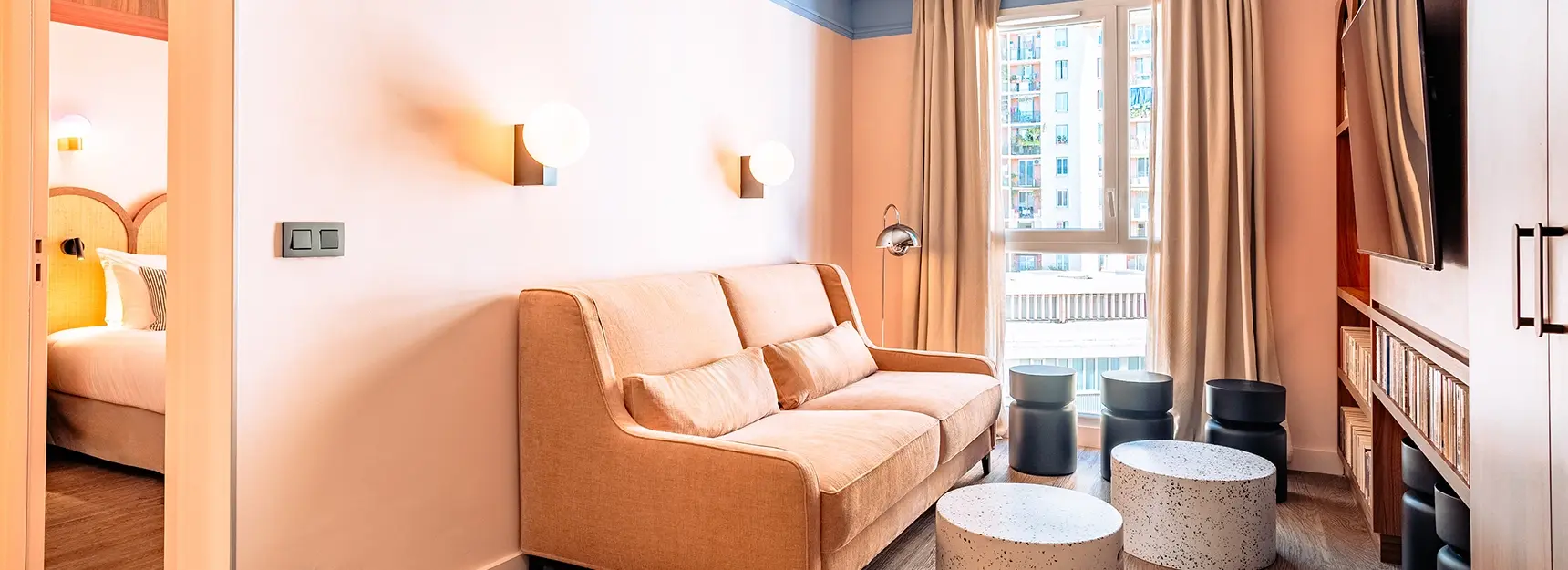 Coin salon avec canapé et télé et une chambre à gauche – RockyPop Marseille
