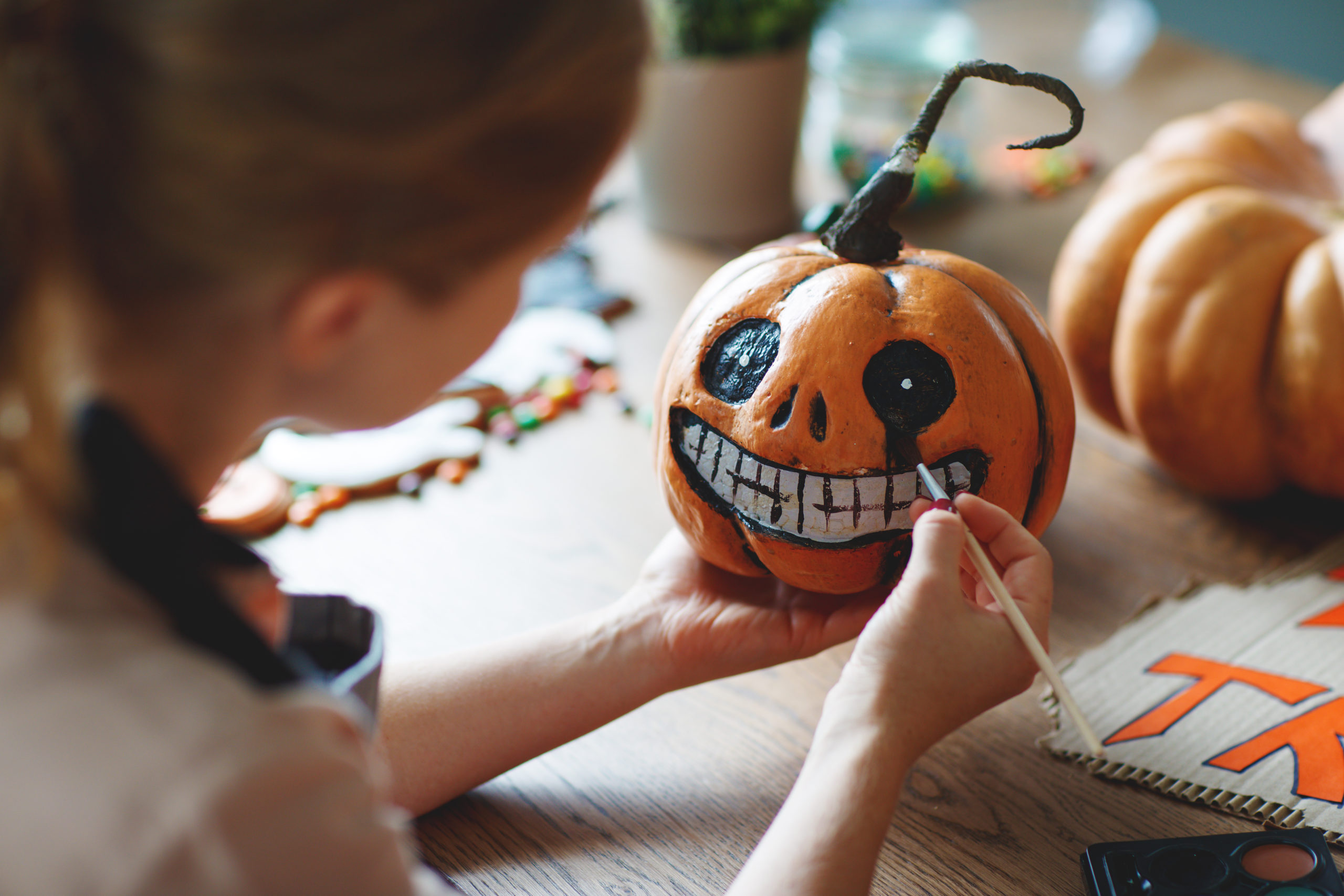 woman artist prepares for halloween and paints pumpkins